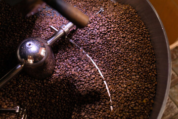process of preparing, roasting fresh raw coffee beans grain in coffee roaster professional machine. soft focus.