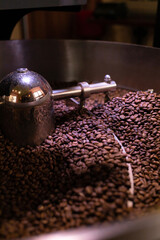 process of preparing, roasting fresh raw coffee beans grain in coffee roaster professional machine. soft focus.  vertical