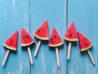 Slice watermelon popsicle sticks top view on blue color wooden table for summer fruit concept. - Powered by Adobe
