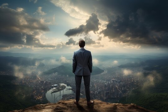 A businessman stands on top of a mountain and looks at the city. Symbol of success and career. 