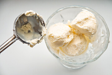 Scoops of ice cream in a glass jar and a dispenser-spoon for ice cream. Close-up