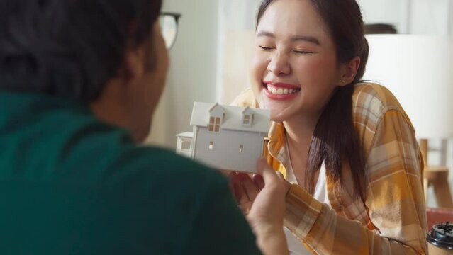 happiness dream home is coming asian sweet marry couple joyful moment hand holding house design model together with full of dream and positive feeling future  while sit talk together at home 