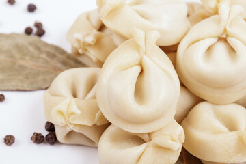 Uncooked dumplings with peppercorns and bay leaves on white background. Dumplings closeup.