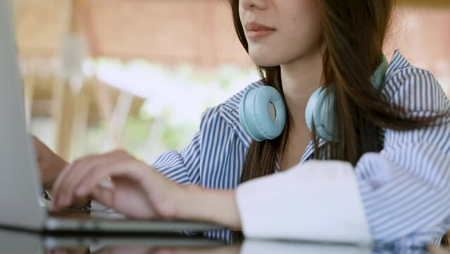 Close-up cool blue headphones that lady puts on neck after listening music, asian woman unhooks headphones neck, in order sit work requires lot concentration, in order work fullest, not make mistakes.