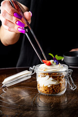 woman hand decorated carrot cake in a glass jar on table