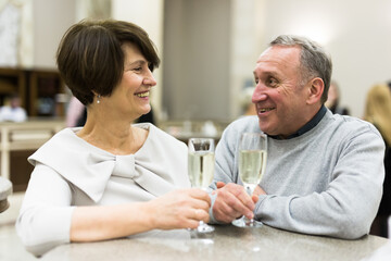 Mature man and woman drinking champagne in theater lobby