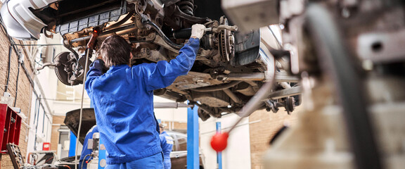 Car mechanic inspecting car steering rod and repair suspension detail. Lifted automobile at repair...