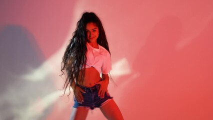 Beautiful girl with long black hair dances modern dance on red background