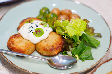 A plate with cutlets, new potatoes, Brussels sprouts and lettuce.