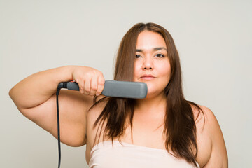 Obese woman in her 30s using a straightening iron