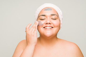 Relaxed plus size woman doing a skin care routine with a mud mask