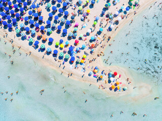 Aerial view on beach, people and umbrellas. Vacation and adventure. Europe, Mediterranean Sea. Top view from drone at beach and azure sea. View on the coast from drone.