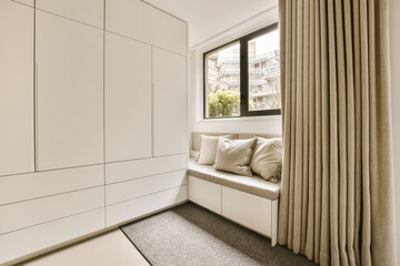 a living room with white cabinets and beige drapes on the window seat is in front of the sliding door
