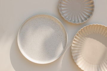 Three different size stoneware plates on beige table background. Flat lay, top view. Natural color...