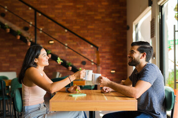 Cheerful couple talking and having fun while drinking coffee