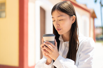 Pretty Chinese woman at outdoors holding a take away coffee