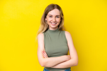 Blonde English young girl isolated on yellow background with arms crossed and looking forward