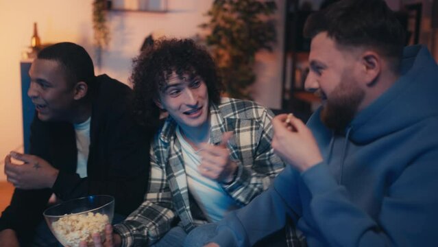 Side view of diverse male friends enjoying watching comedy together, fun