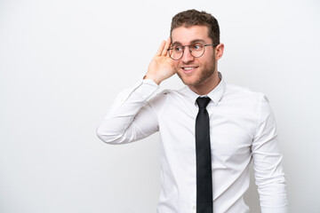 Young business caucasian man isolated on white background listening to something by putting hand on the ear
