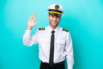 Airplane caucasian pilot isolated on blue background saluting with hand with happy expression