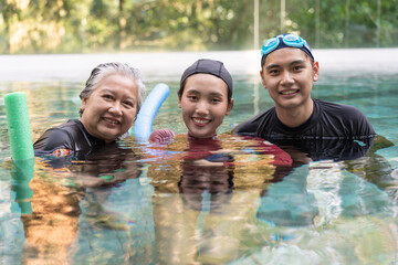 Young trainer helping senior woman in aqua aerobics and working out in the pool. old woman and...