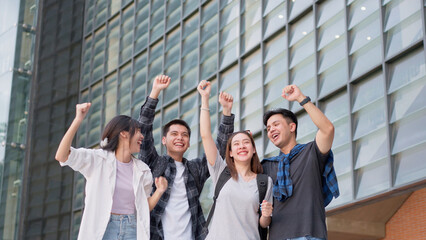 Group of happy young entrepreneurs with hands up and laughing to celebrate and excited success for...