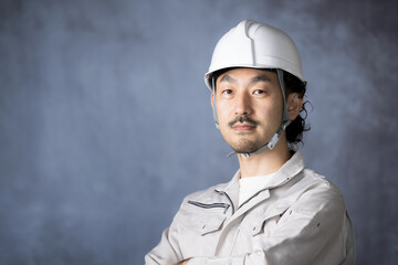 作業着で腕を組むヘルメットの日本人中年男性　ガテン系の転職や採用にも