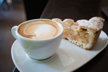 Piece of an apple pie and cup of coffee espresso on wooden table. Shallow focus