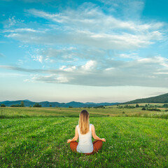 Fototapeta na wymiar Woman doing yoga on the green grass at the mountain. Carpathians