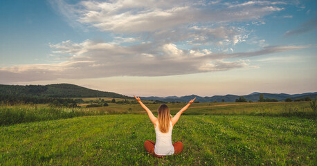 Woman doing yoga on the green grass at the mountain. Carpathians