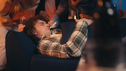 Group of young people drawing mustache on friend's face, playing a prank