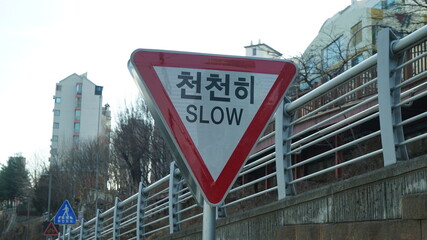 Traffic sign on Korean street, text means slow down