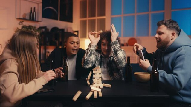 Slow motion of funny young people playing jenga, leaning wooden blocks tower