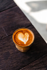 Stylish cappuccino with heart foam on a wooden background, side view
