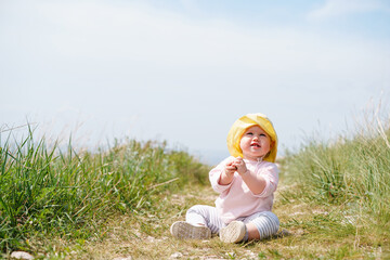 Fototapeta premium Cute baby toddler in a panama hat is sitting on the path, active childhood in the fresh air