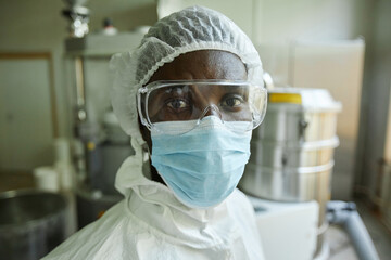 Closeup portrait of young black man wearing mask and protective suit while working at factory