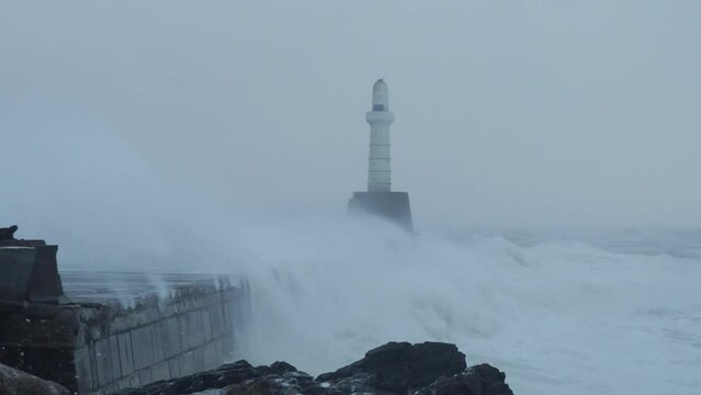 Waves hitting the breakwater at the entrance to Aberdeen Harbour, Scotland, during stormy weather