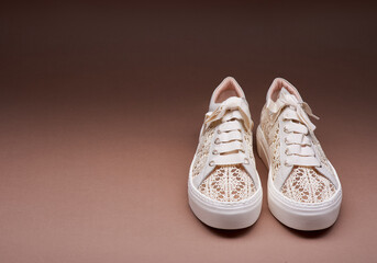 Trendy pastel knitted design sneakers with white thick rubber soles on a gradient brown background...
