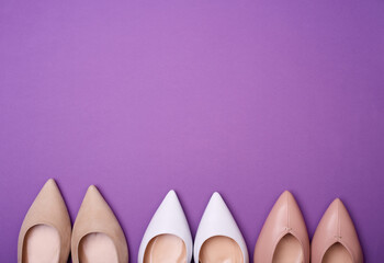 Three pairs of elegant shoes on the purple background.