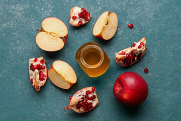 Jar of honey with pomegranate and apples for Rosh Hashanah celebration (Jewish New Year) on blue background