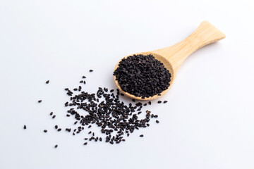 Close-up black cumin, black caraway (Nigella sativa) herb ingredient in wooden spoon isolated on white background.