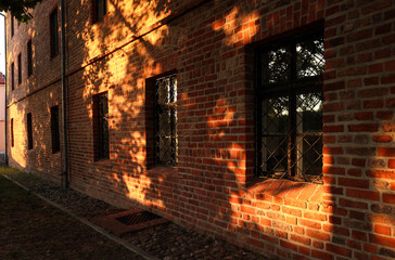 Okna w ceglanej ścianie oświetlone późnym słońcem.