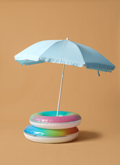 Swim rings with beach umbrella on beige background