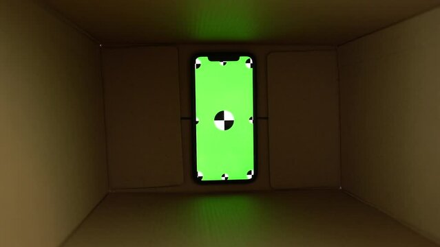 smartphone with chromakey green screen inside in dark box zoom out. delivery package. m-commerce concept. shopping from phone. package delivery. High quality 4k footage