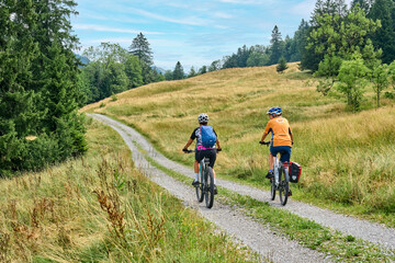 two senior girlfriends having fun during a cycling tour in the Allgau Alps near Oberstaufen,...