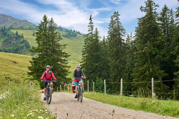 Fototapeta premium two senior girlfriends having fun during a cycling tour in the Allgau Alps near Oberstaufen, Bavaria, Germany