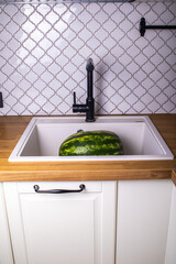watermelon washed under running water in the sink