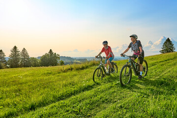 two senior girlfriends having fun during a cycling tour in the Allgau Alps near Oberstaufen, Bavaria, Germany - obrazy, fototapety, plakaty