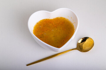 soup in a bowl, a golden spoon lies nearby
