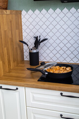 turkey goulash in a frying pan on a stove in a kitchen interior